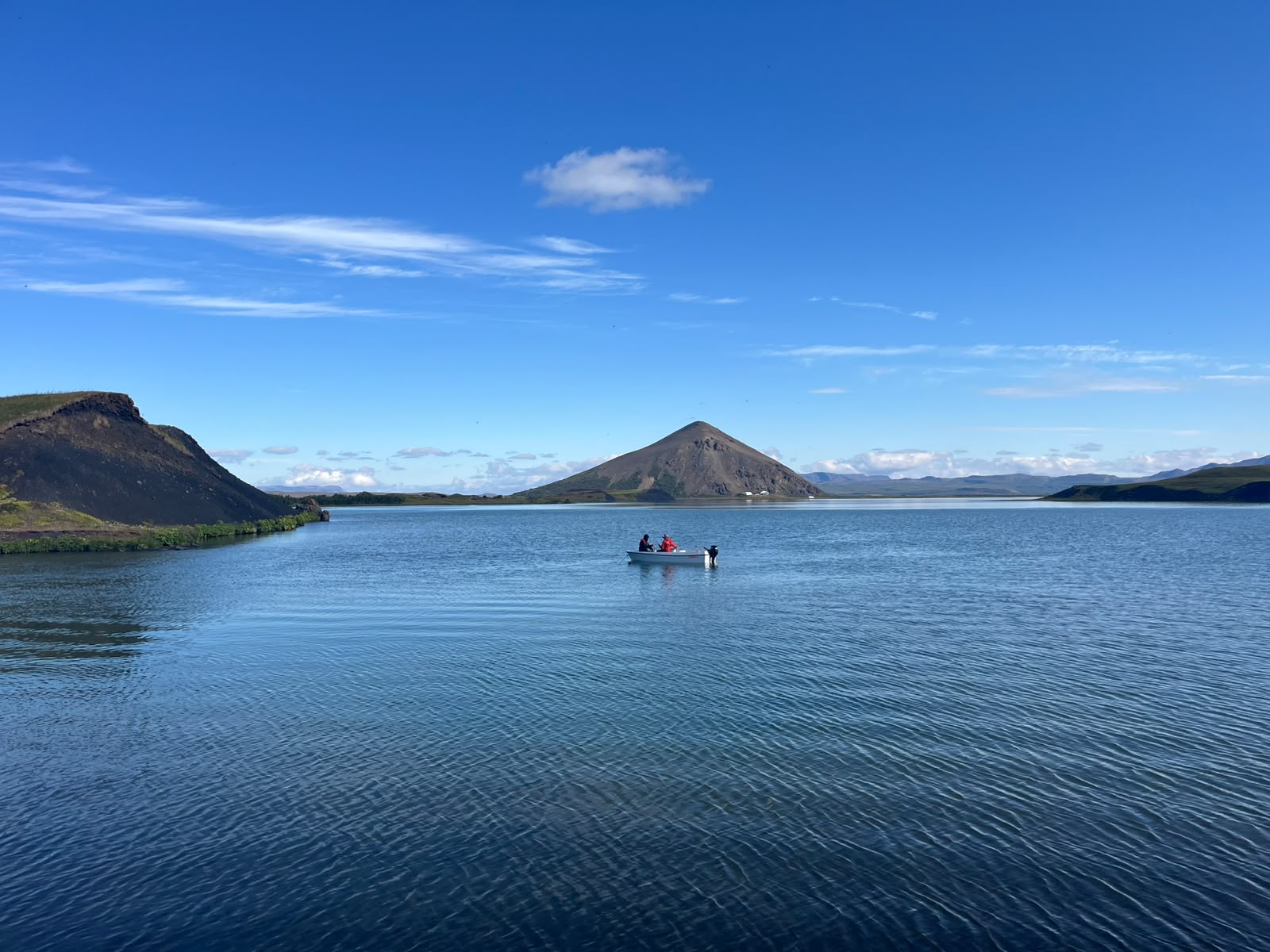 A photo of a small boat on a smooth lake.